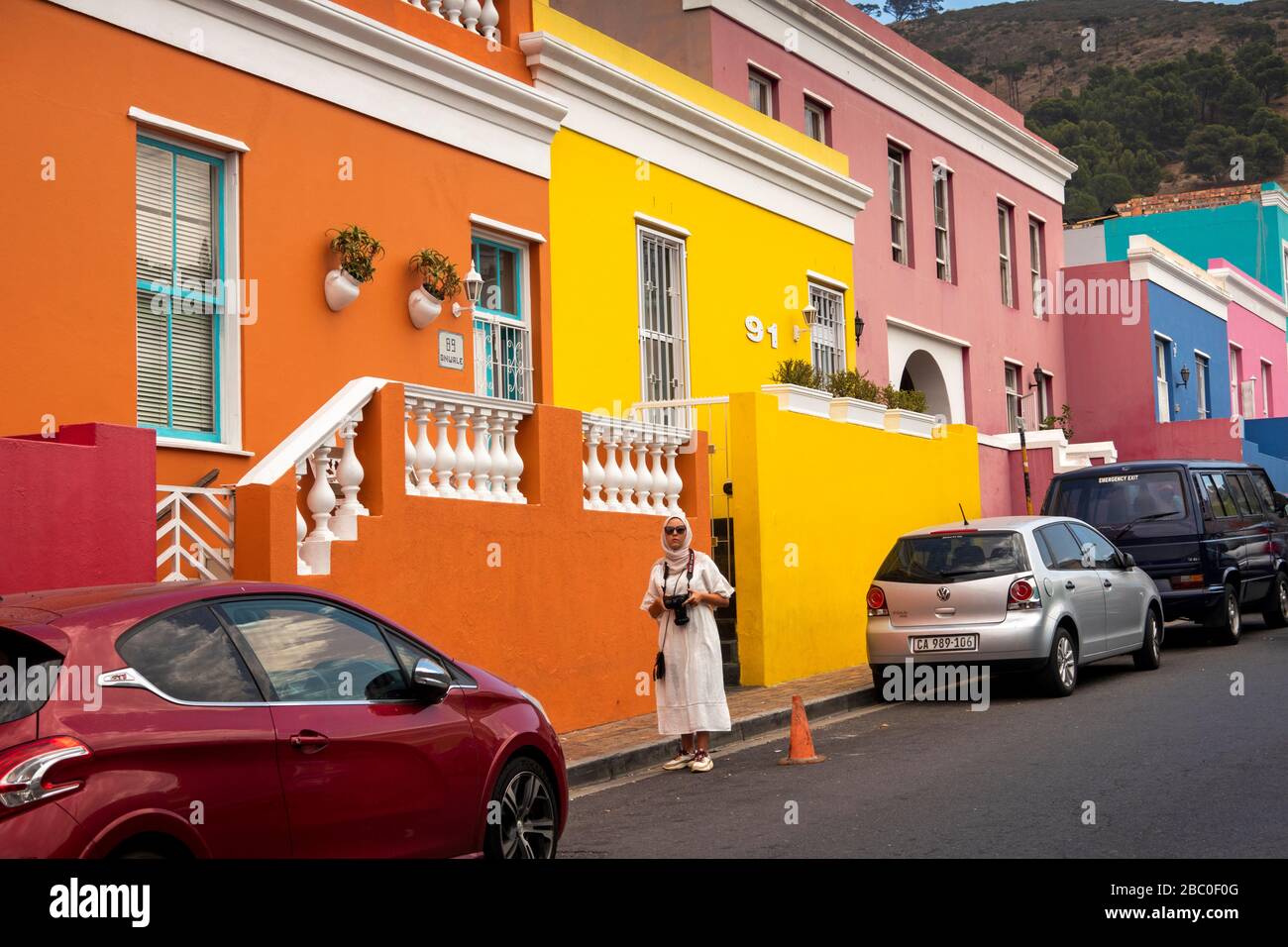 Afrique du Sud, le Cap, Schotsche Knoof, Bo Kaap, Wale St, femme garante une place de stationnement de voiture de maison rénovée colorée Banque D'Images Afrique du Sud, le Cap, Schotsche Knoof, Bo Kaap, Wale St, femme garante une place de stationnement de voiture de maison rénovée colorée Banque D'Images