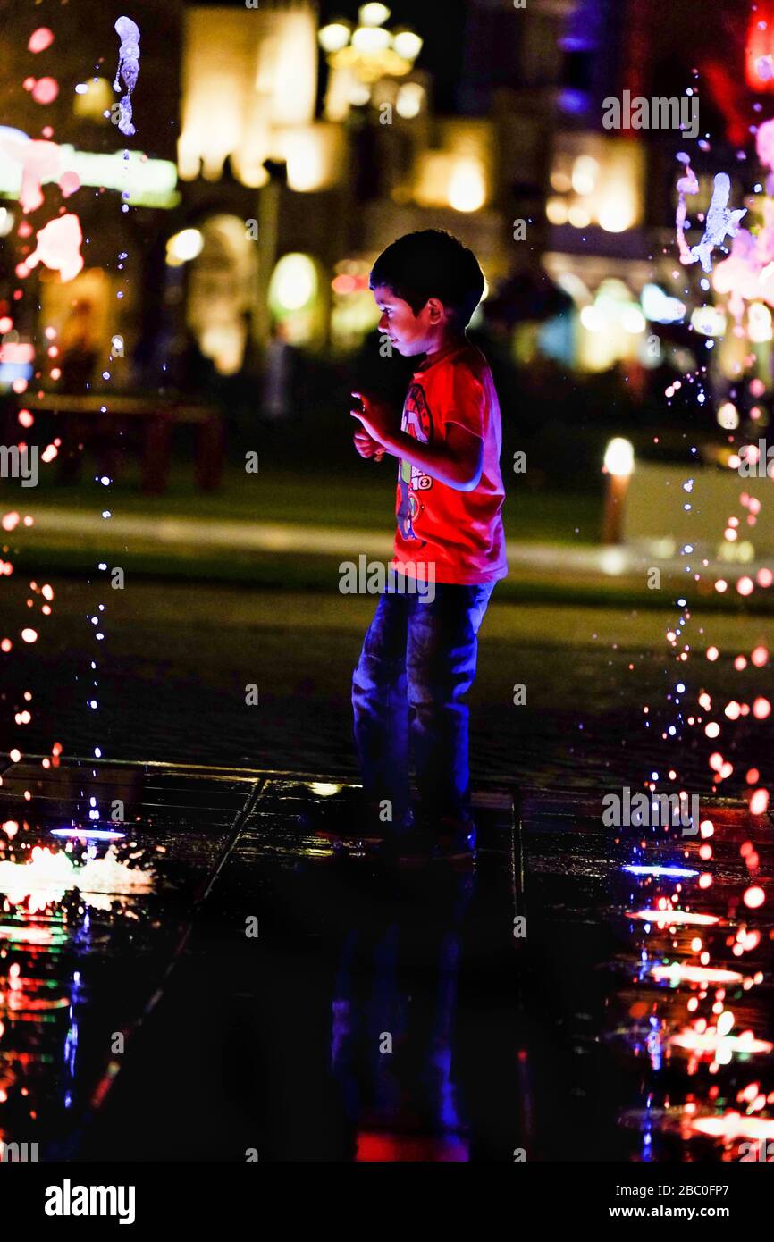 Enfant qui traverse des fontaines à Global Village, Dubaï, Émirats arabes Unis. Global Village combine des cultures de 90 pays à travers le monde en un seul endroit. Banque D'Images