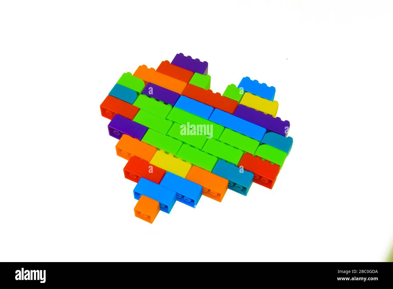 Forme de coeur faite avec beaucoup de différents blocs de construction de couleur devant un arrière-plan blanc isolé Banque D'Images