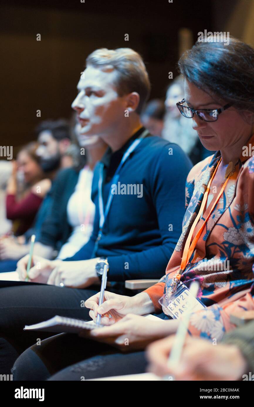 Femme d'affaires attentive prenant des notes dans le public de la conférence Banque D'Images