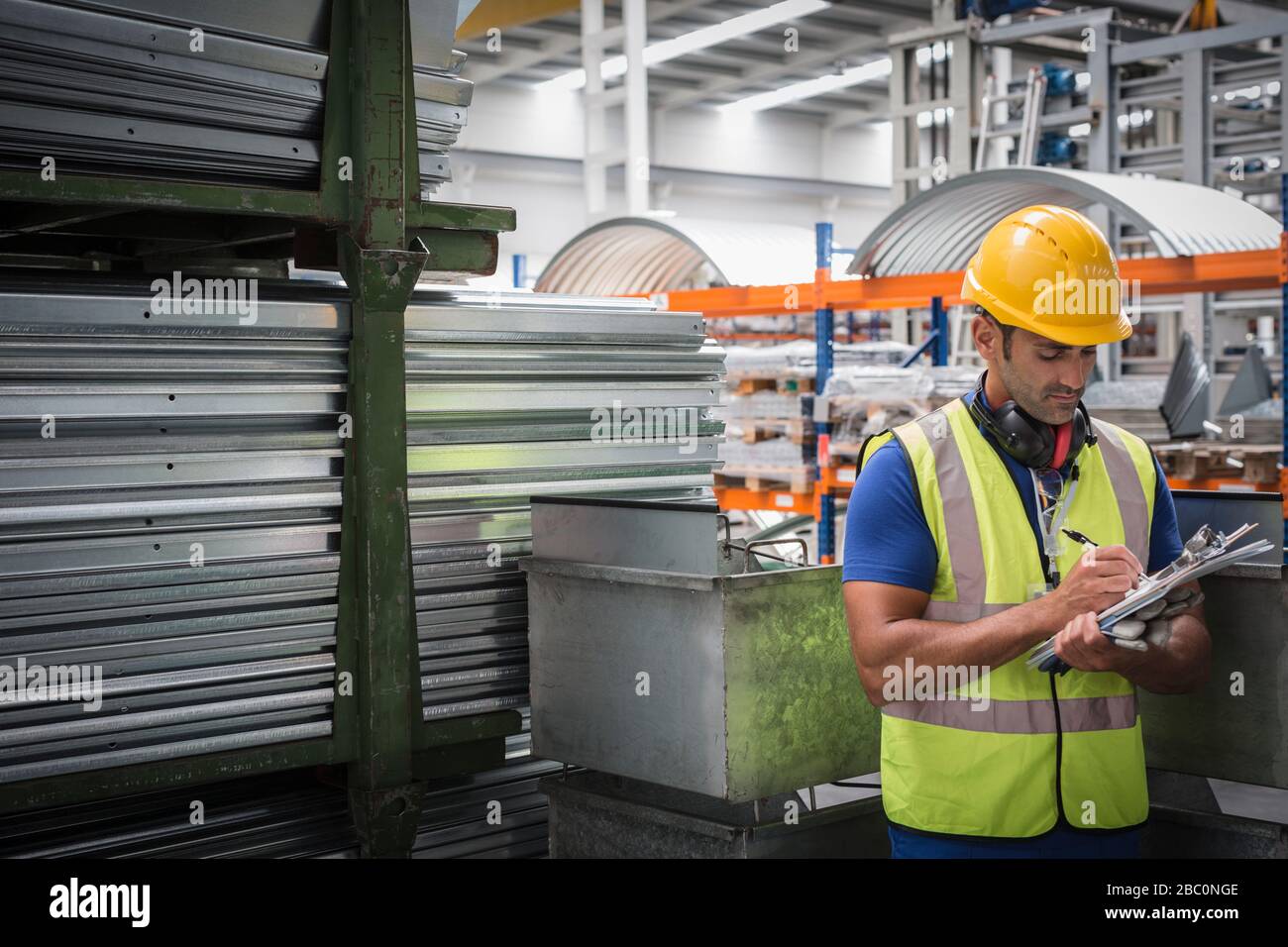 Travailleur masculin avec presse-papiers travaillant dans l'usine d'acier Banque D'Images