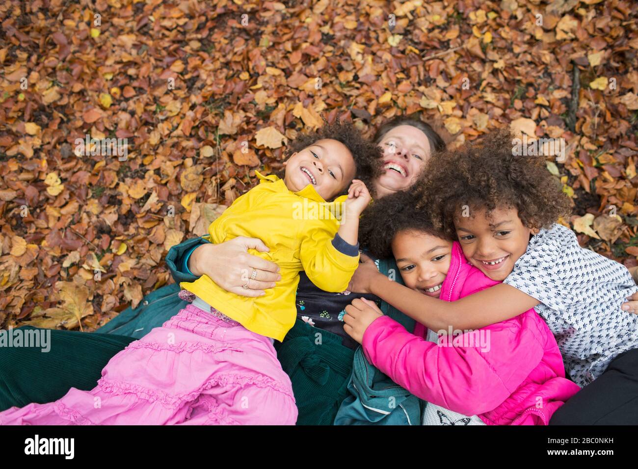 Portrait bonne mère et enfants pontant en feuilles d'automne Banque D'Images