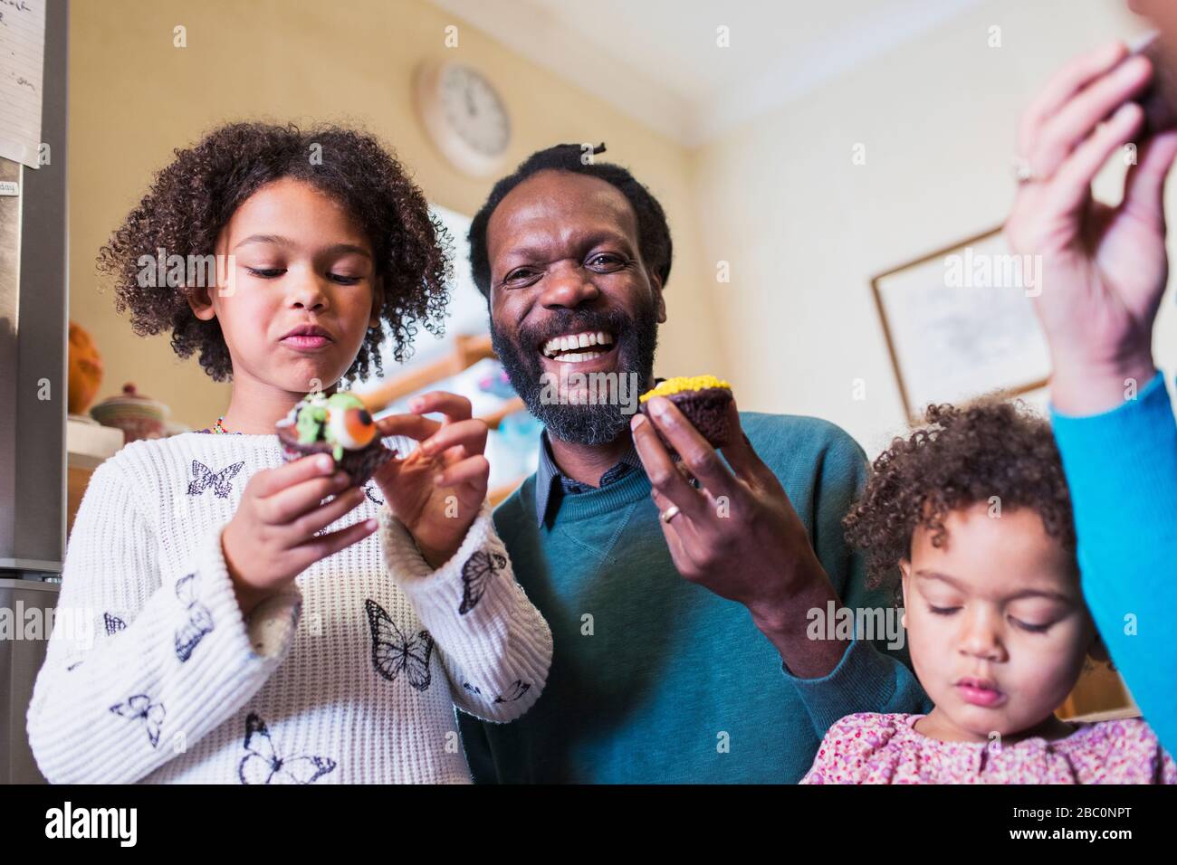 Portrait heureux père et filles manger des cupcakes Banque D'Images