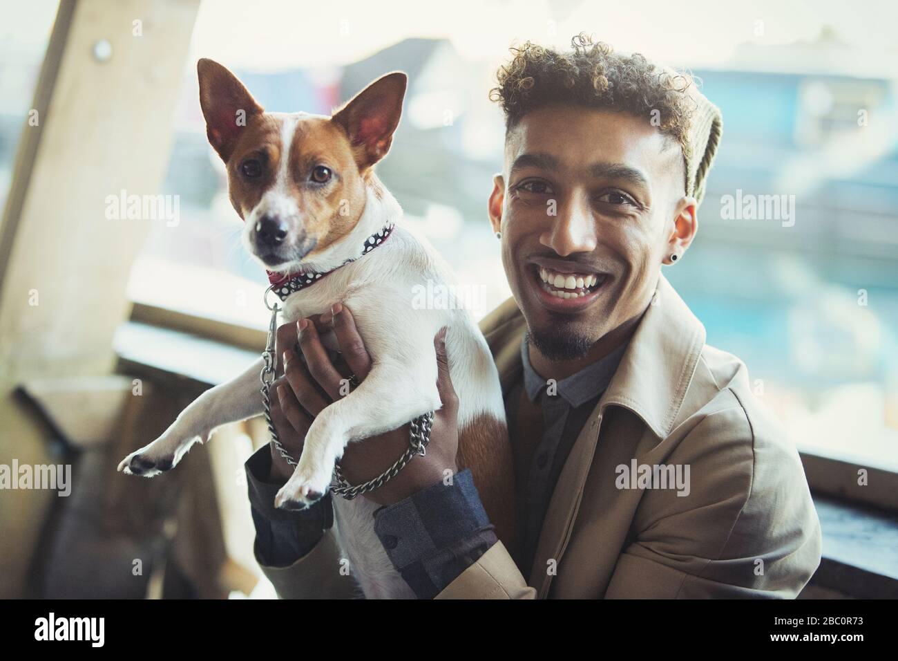 Portrait souriant jeune homme tenant chien Banque D'Images