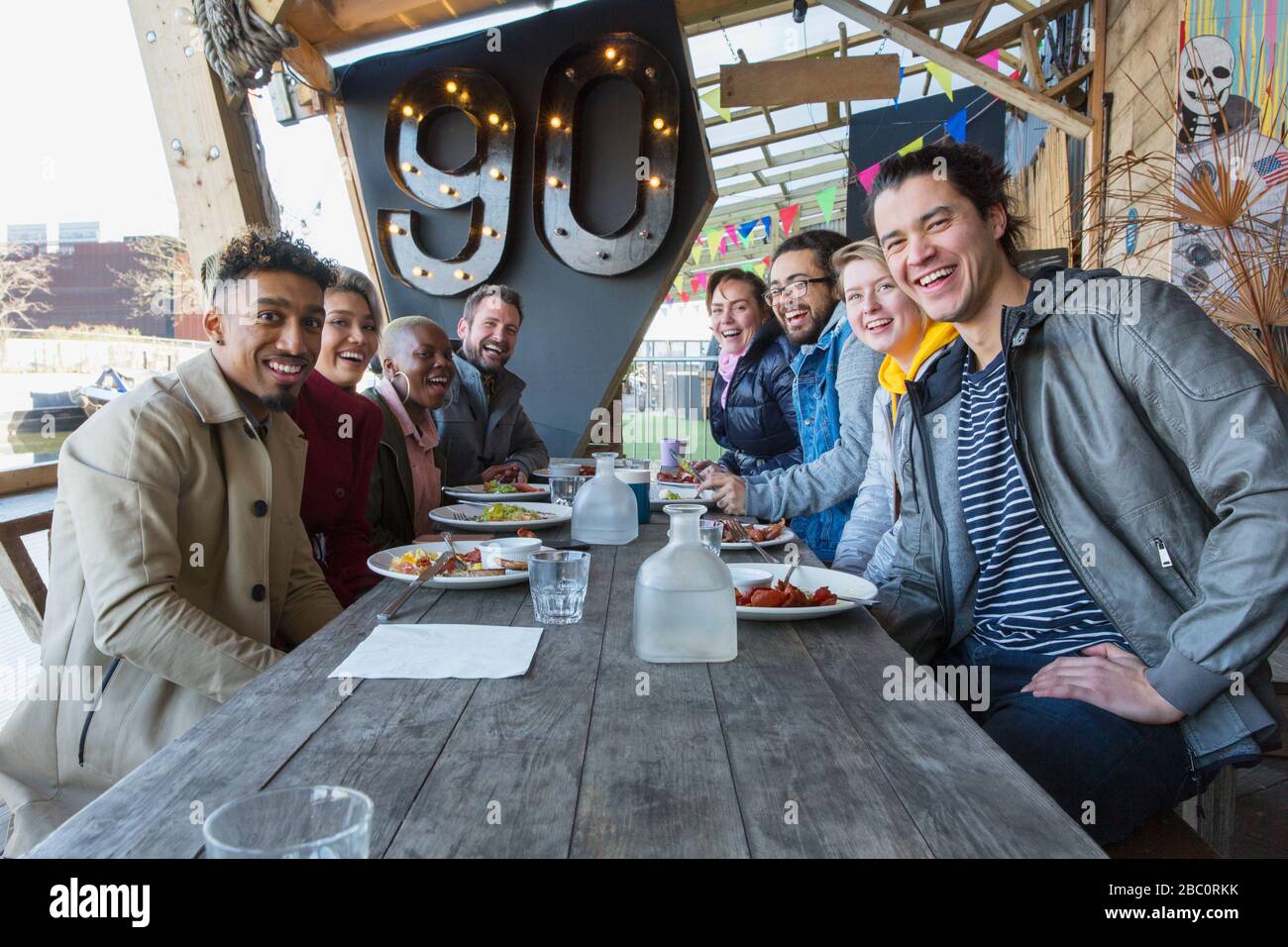 Portrait souriant amis manger au restaurant patio extérieur Banque D'Images