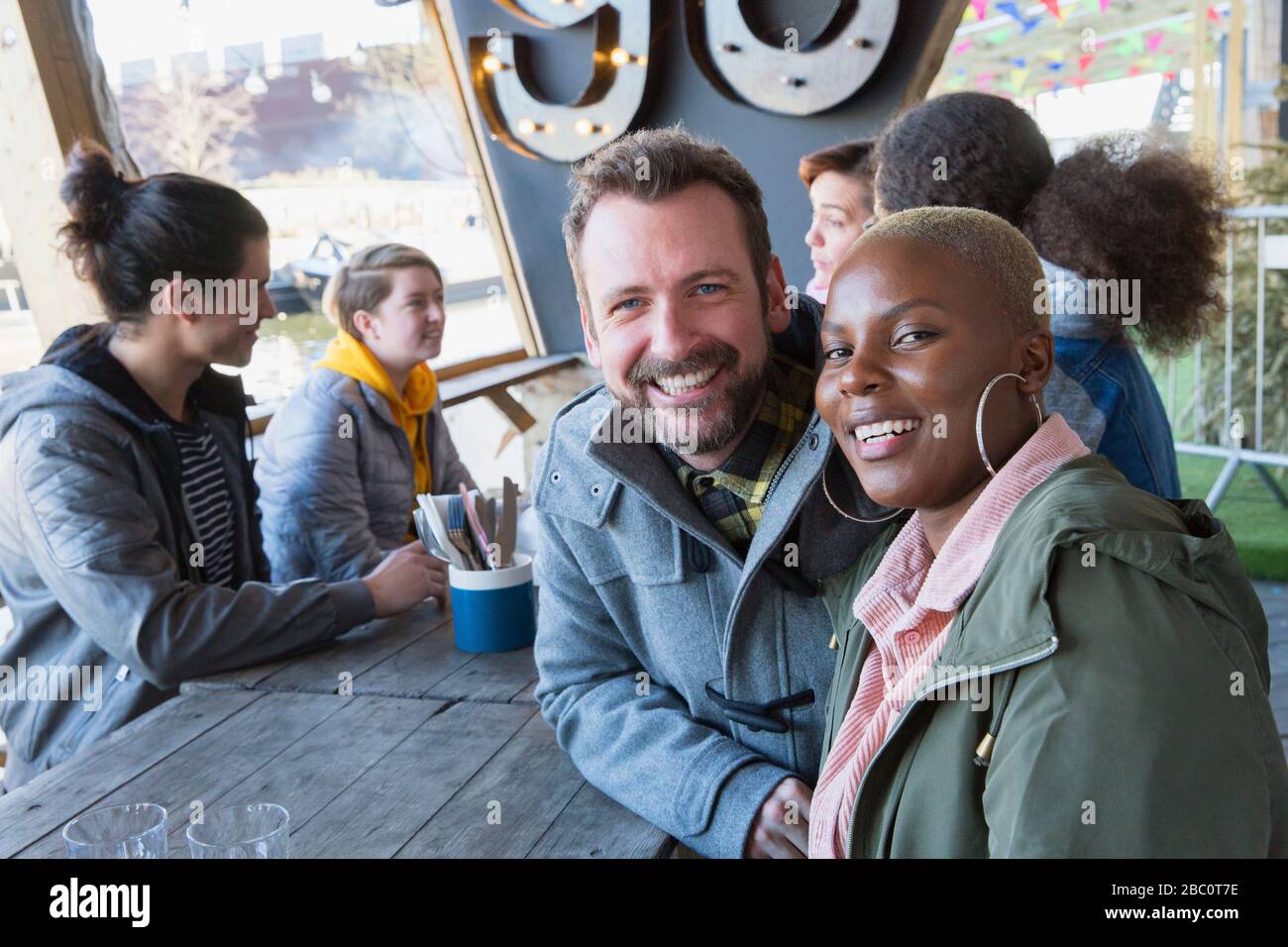 Portrait souriant couple dîner avec des amis au restaurant patio extérieur Banque D'Images