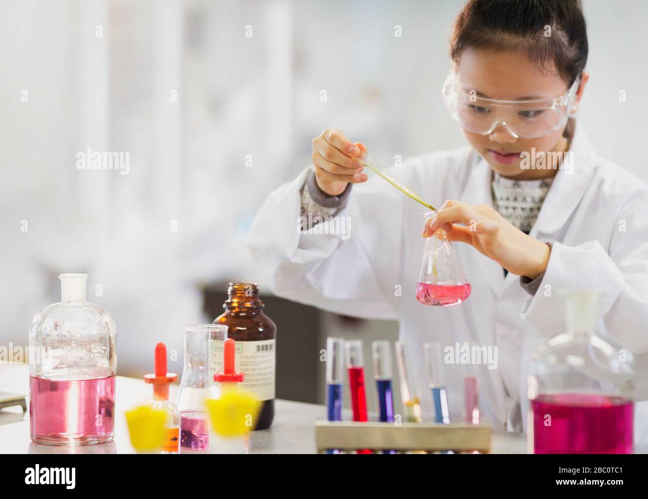 Une jeune étudiante qui effectue une expérience scientifique en salle de classe de laboratoire Banque D'Images
