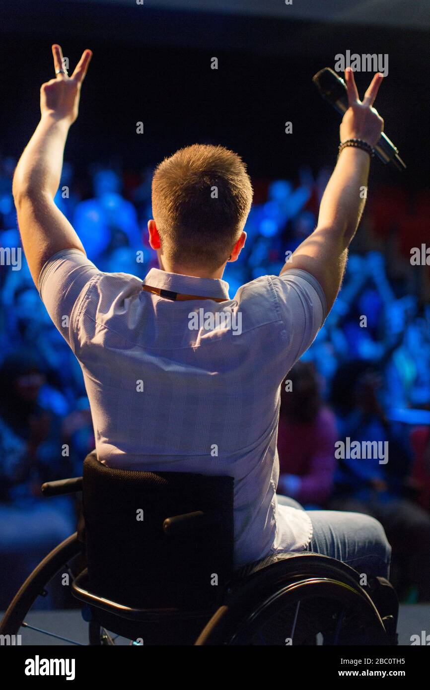 Enceinte féminine en fauteuil roulant gestant le signe de la paix sur scène Banque D'Images