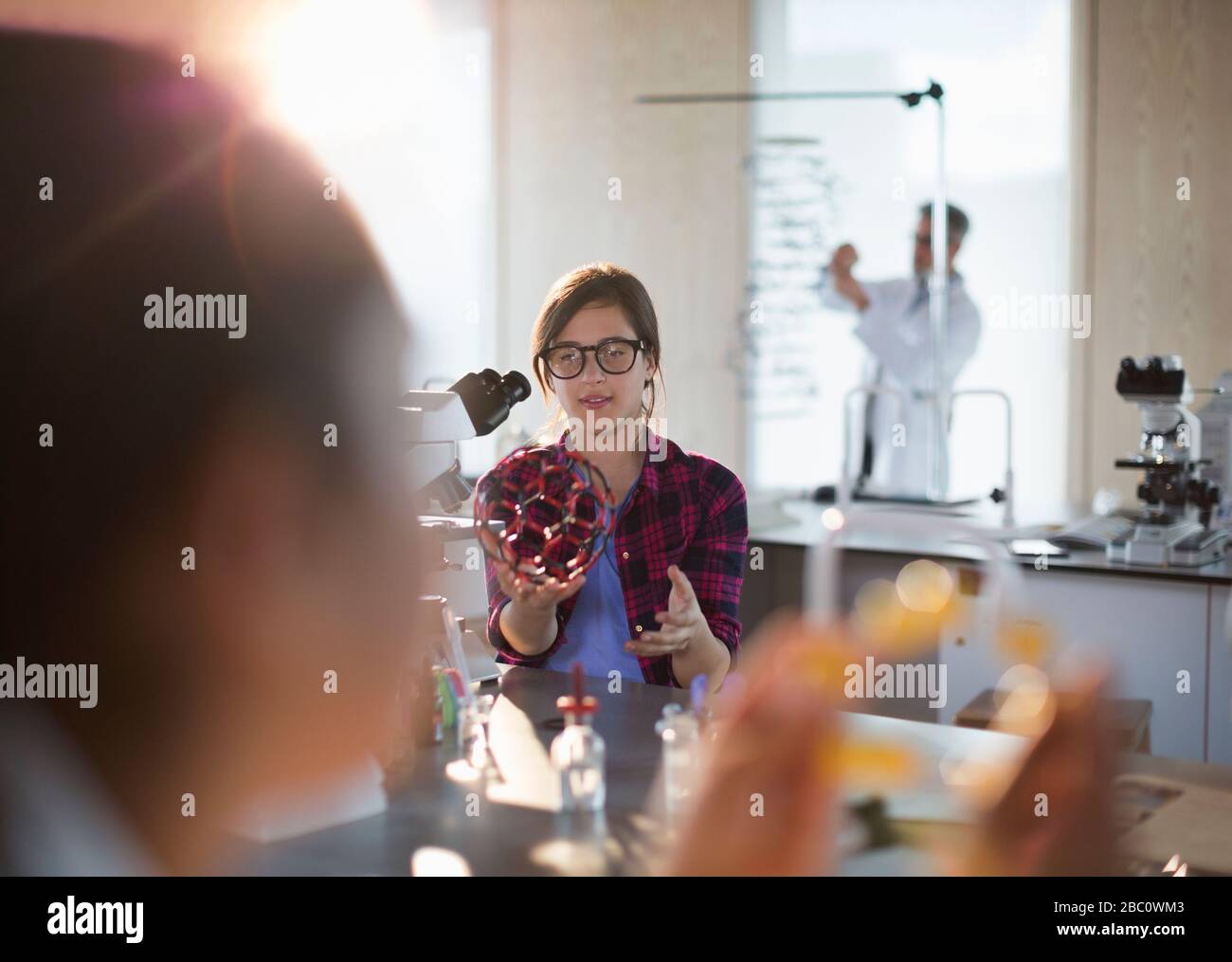 Jeune fille étudiant tenant la structure moléculaire au microscope en salle de classe de laboratoire Banque D'Images