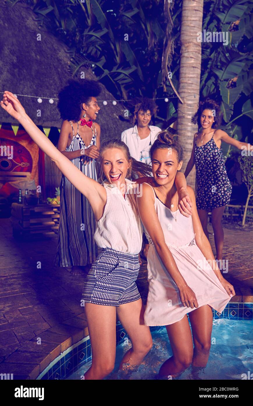 Portrait exubérant jeunes femmes amis paring, danse et passage à gué à la fête de la piscine Banque D'Images