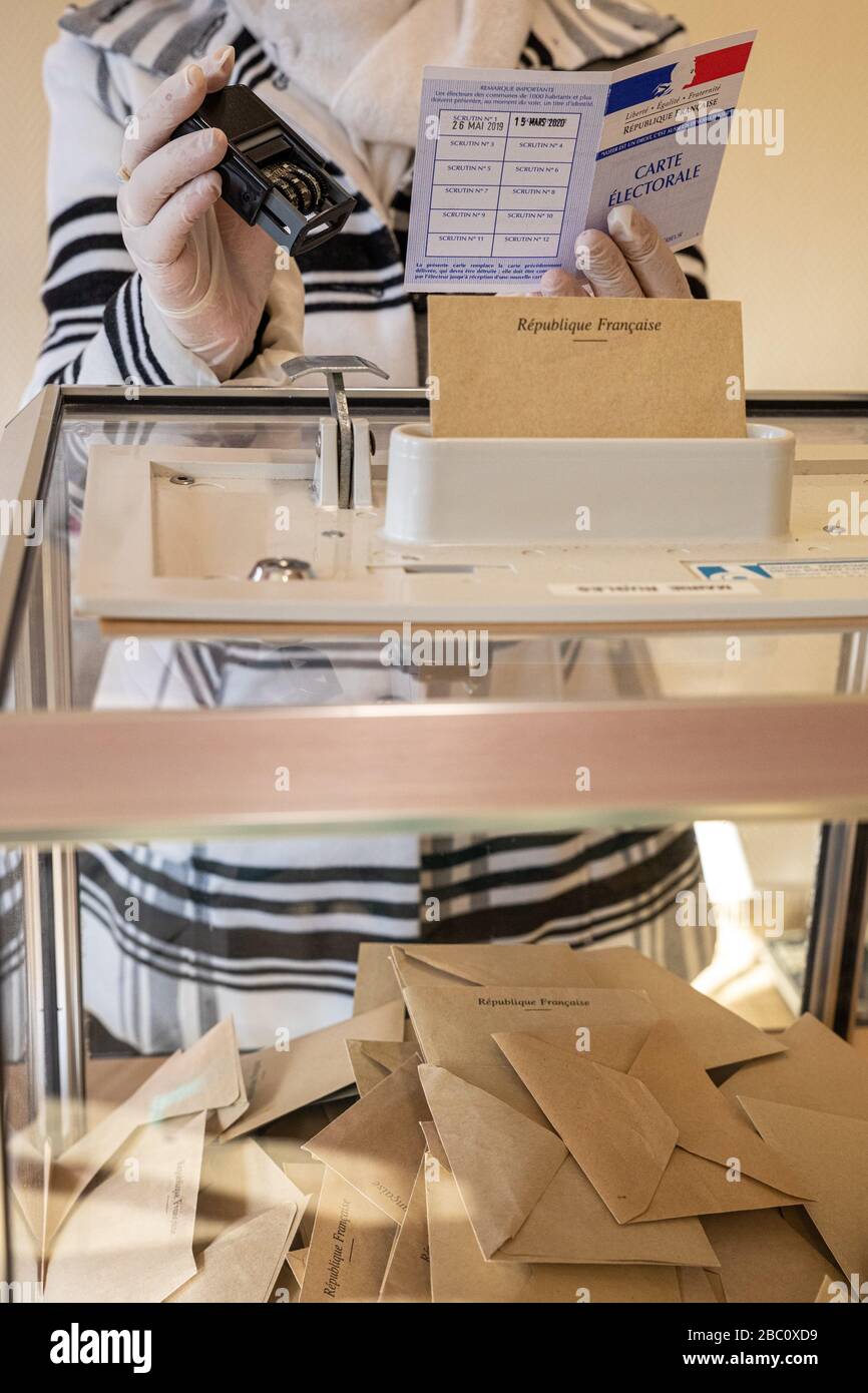 VÉRIFICATION DE LA CARTE DE L'ÉLECTEUR BFORE LE VOTE, LORS DU PREMIER TOUR DES ÉLECTIONS MUNICIPALES, TOUT EN RESPECTANT LES MESURES SANITAIRES PRISES À LA LUMIÈRE DE LA PANDÉMIE DE CORONAVIRUS, POSTE DE VOTE À RUGLES, NORMANDIE, FRANCE Banque D'Images