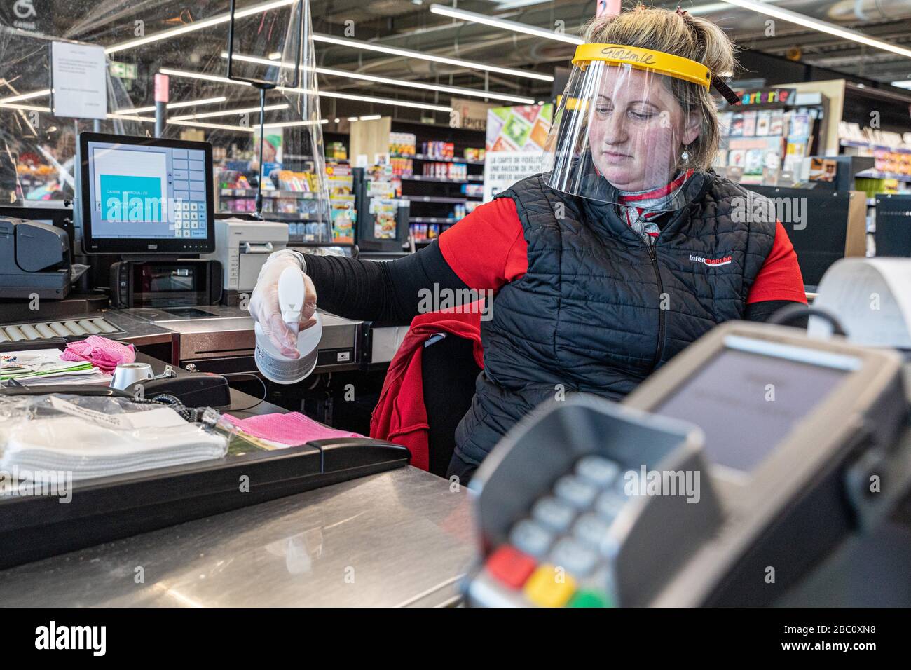 NETTOYAGE DE LA CAISSE ET DU TERMINAL DE CARTE DE CRÉDIT APRÈS CHAQUE CLIENT, CAISSIER DANS UN SUPERMARCHÉ PORTANT UN MASQUE DE PROTECTION ET DES GANTS, ÉPIDÉMIE DE CORONAVIRUS, FRANCE Banque D'Images