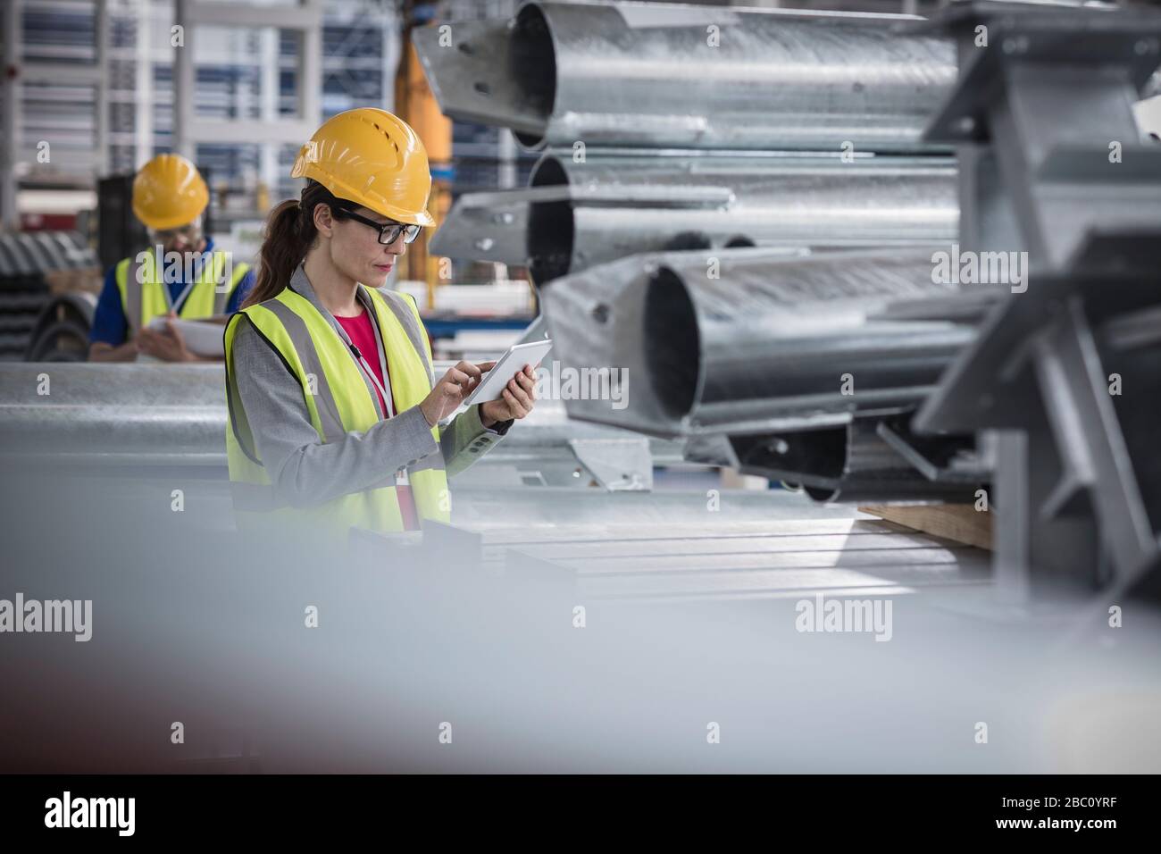 Superviseur femelle utilisant une tablette numérique dans une usine d'acier Banque D'Images