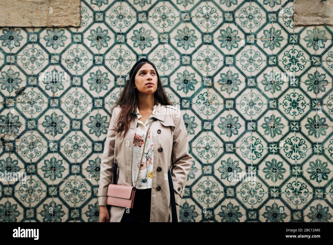Portugal, Lisbonne, Jeune voyageur à la recherche et se tenant sur un mur avec des tuiles typiquement portugaises Banque D'Images