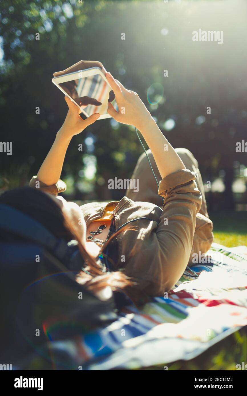 Jeune femme reposant et utilisant une tablette numérique dans un parc ensoleillé d'été Banque D'Images