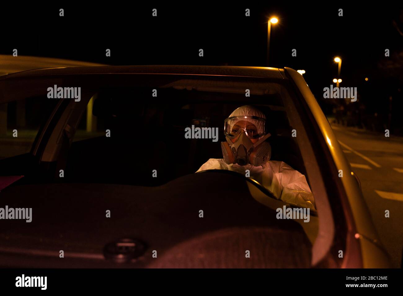 Femme senior portant un costume de protection et masque de voiture de conduite la nuit Banque D'Images