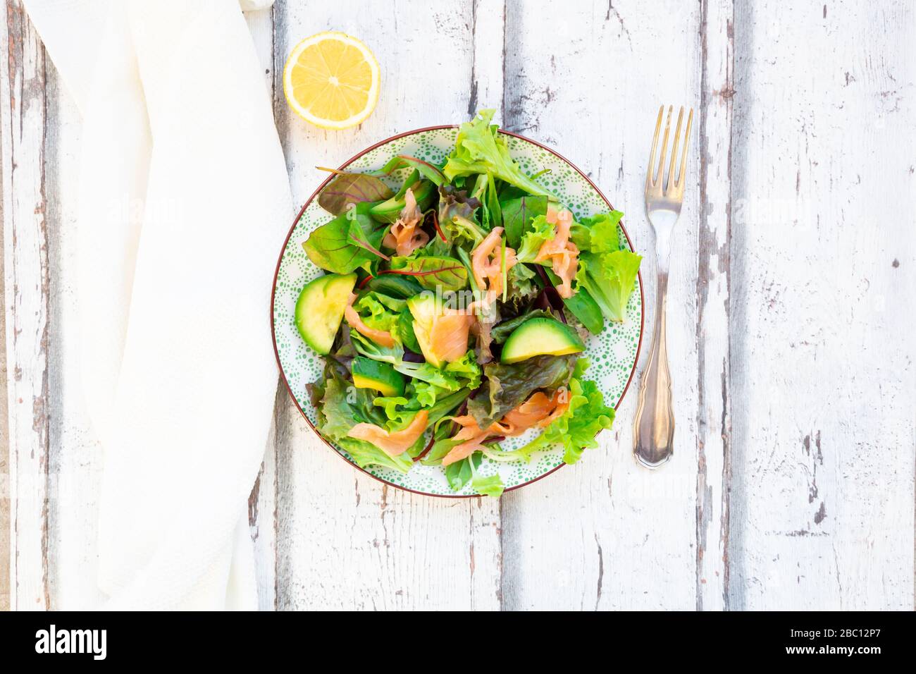 Assiette de salade verte prête à manger avec de l'arugula, de la laitue Lollo Rosso, des jeunes épinards, des feuilles de betterave, de l'avocat, de la salade de maïs et du saumon Banque D'Images