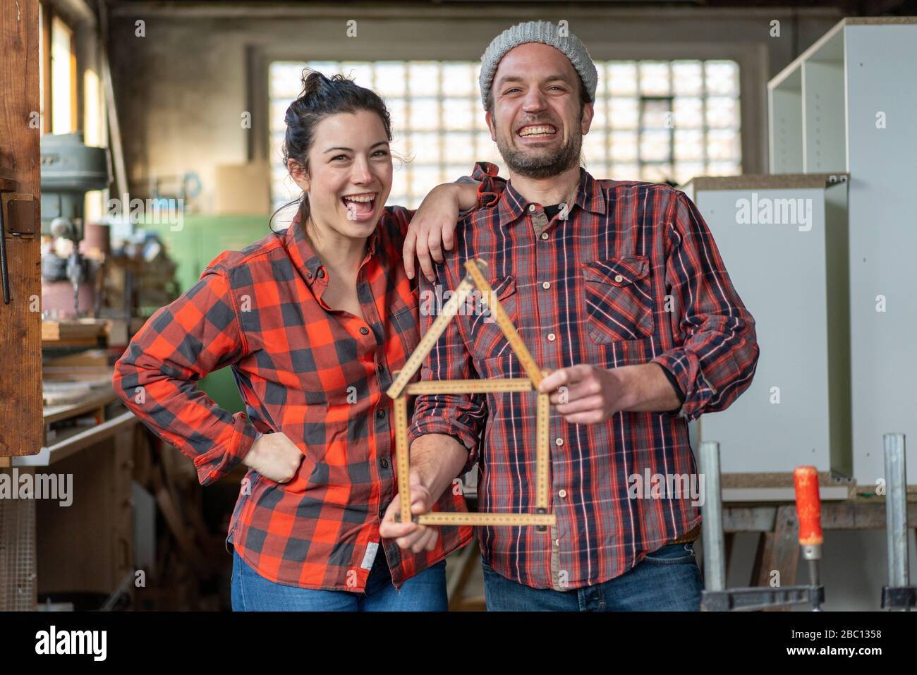 Portrait de l'artisan heureux et de l'artisan tenant yardstick dans leur atelier Banque D'Images