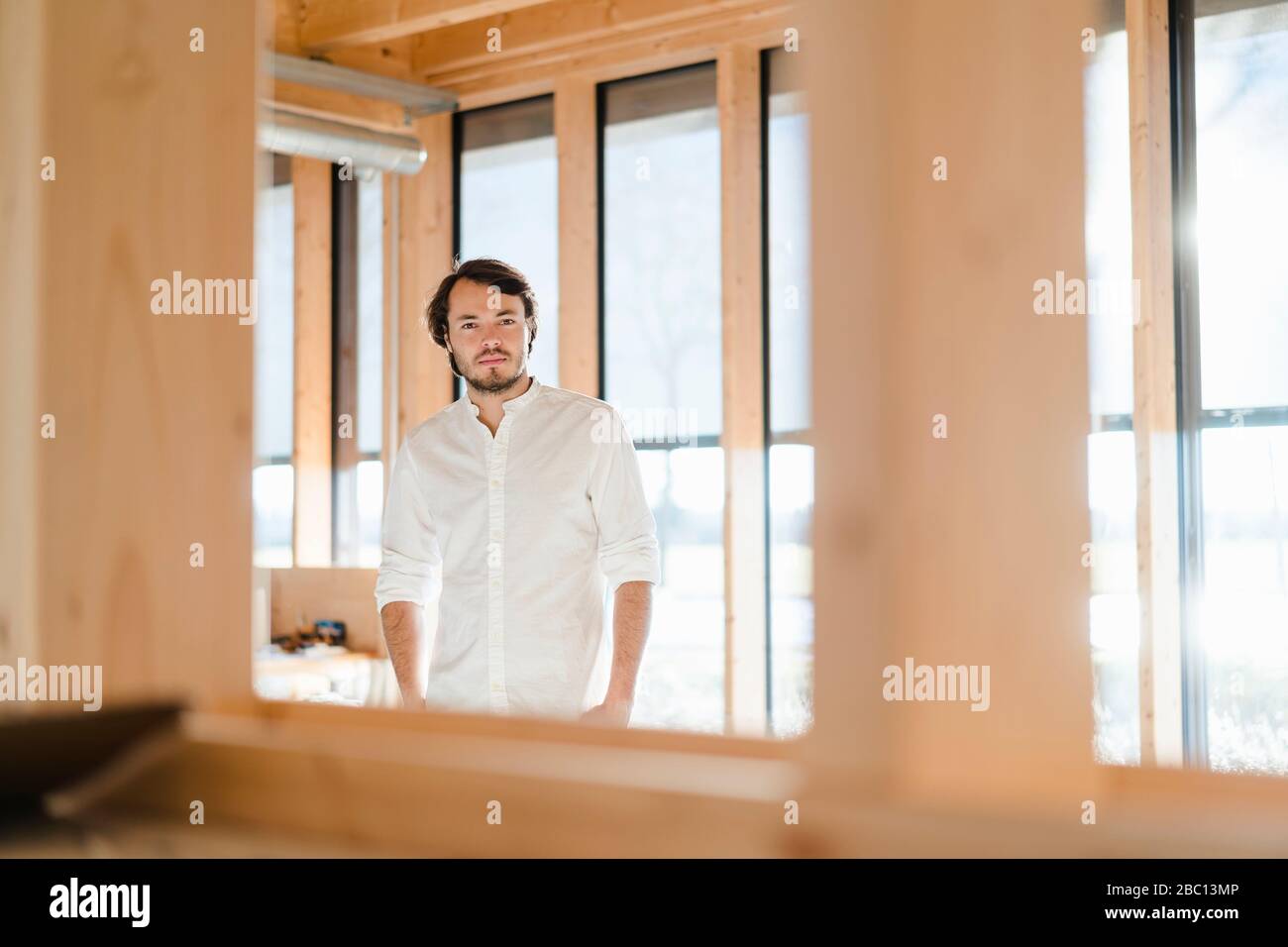 Homme d'affaires debout à la fenêtre dans un bureau en bois ouvert Banque D'Images