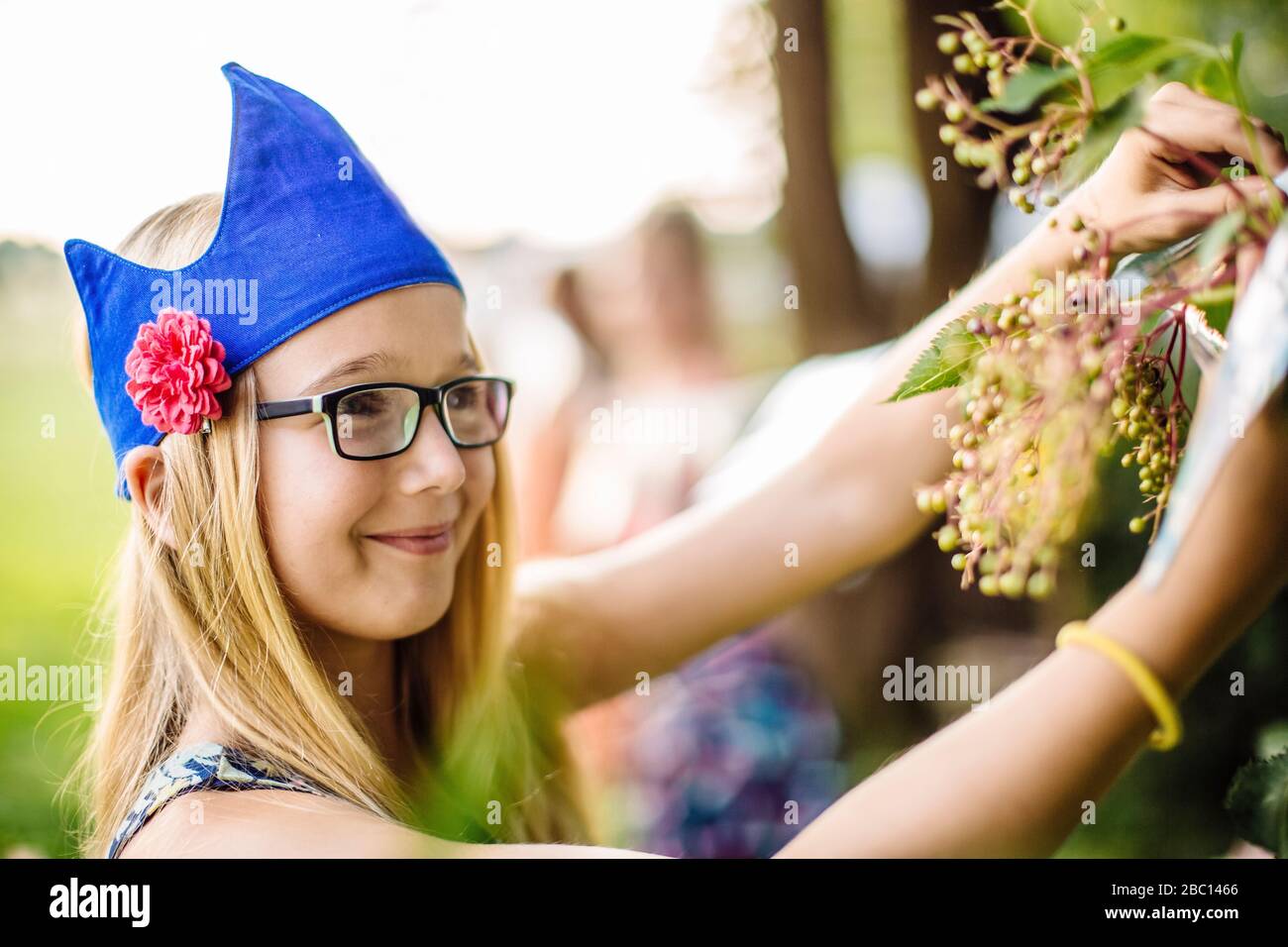 Fille portant un chapeau de fête cueillant des baies de sureau dans le jardin Banque D'Images