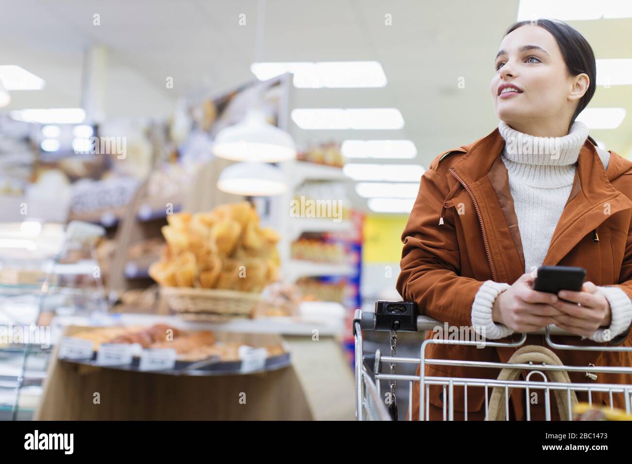 Femme avec un smartphone au supermarché Banque D'Images