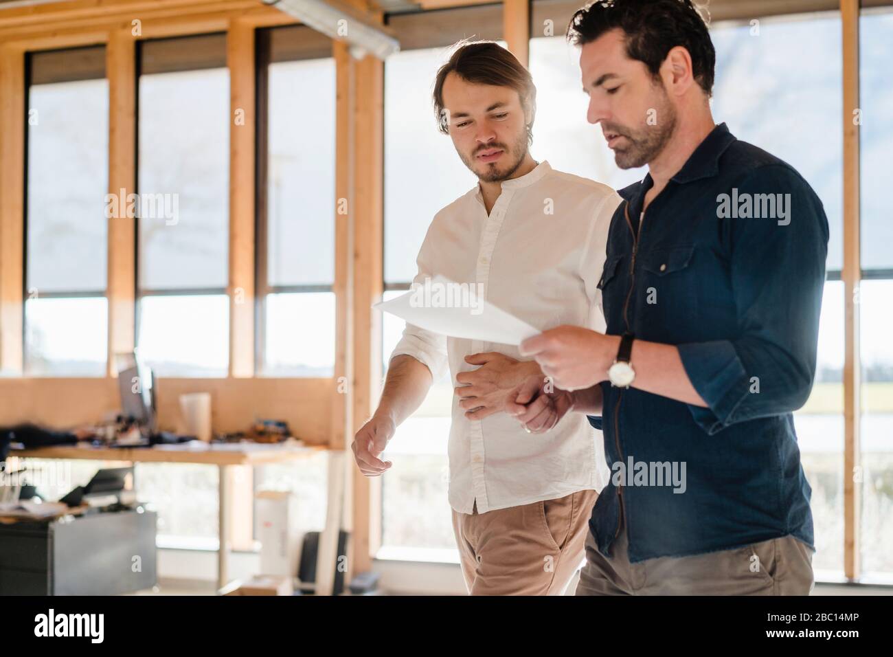 Deux hommes d'affaires avec des documents en bois à l'open-plan bureau Banque D'Images