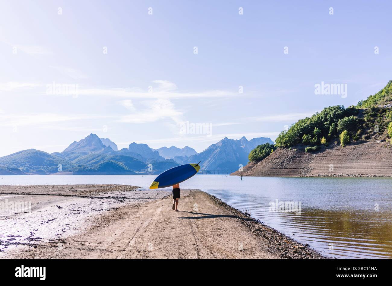 Homme transportant la planche SUP au lac Banque D'Images