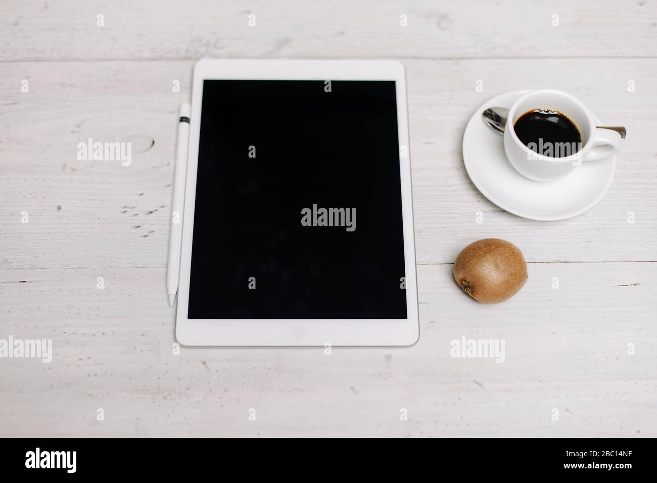 Tablette, tasse de café et kiwi sur surface en bois Banque D'Images
