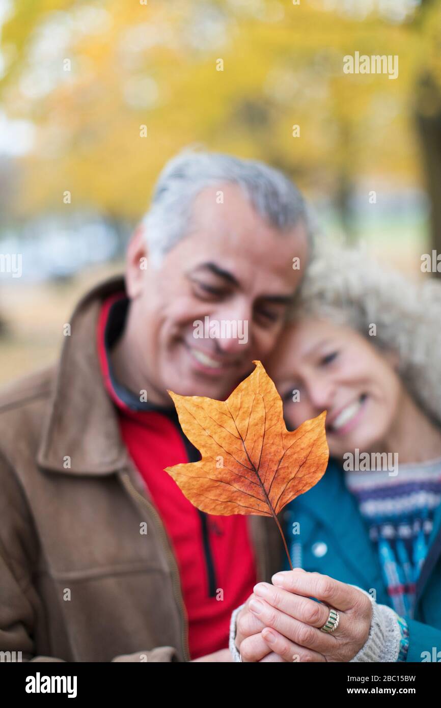 Couple senior affectueux tenant une feuille d'automne orange Banque D'Images