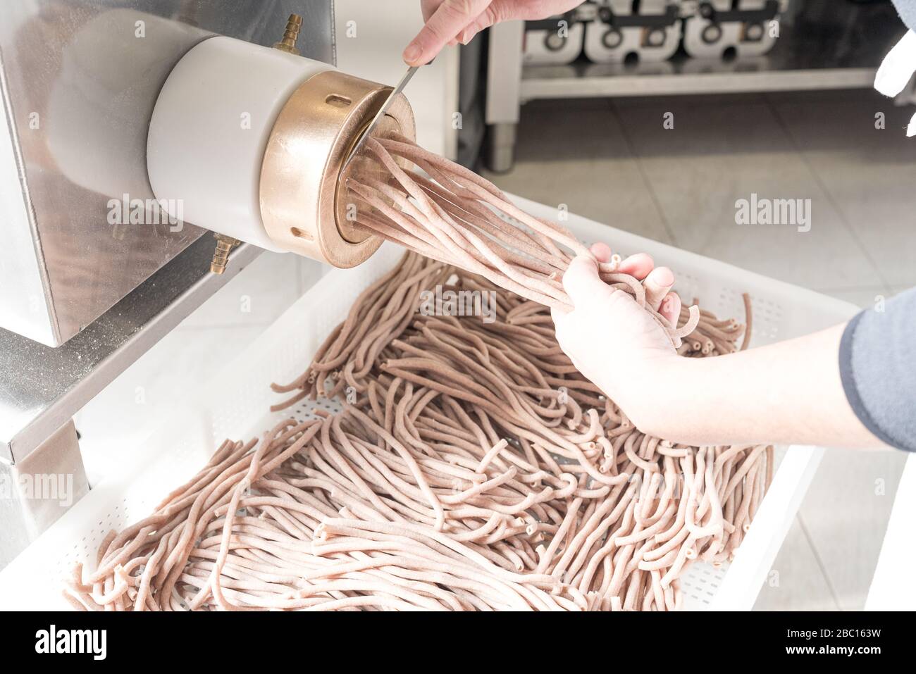 Pâtes fraîches : production de bucatini avec aliments complets, de la farine de semoule encombrement machine et faire cuire au travail, filtre lumineux Banque D'Images