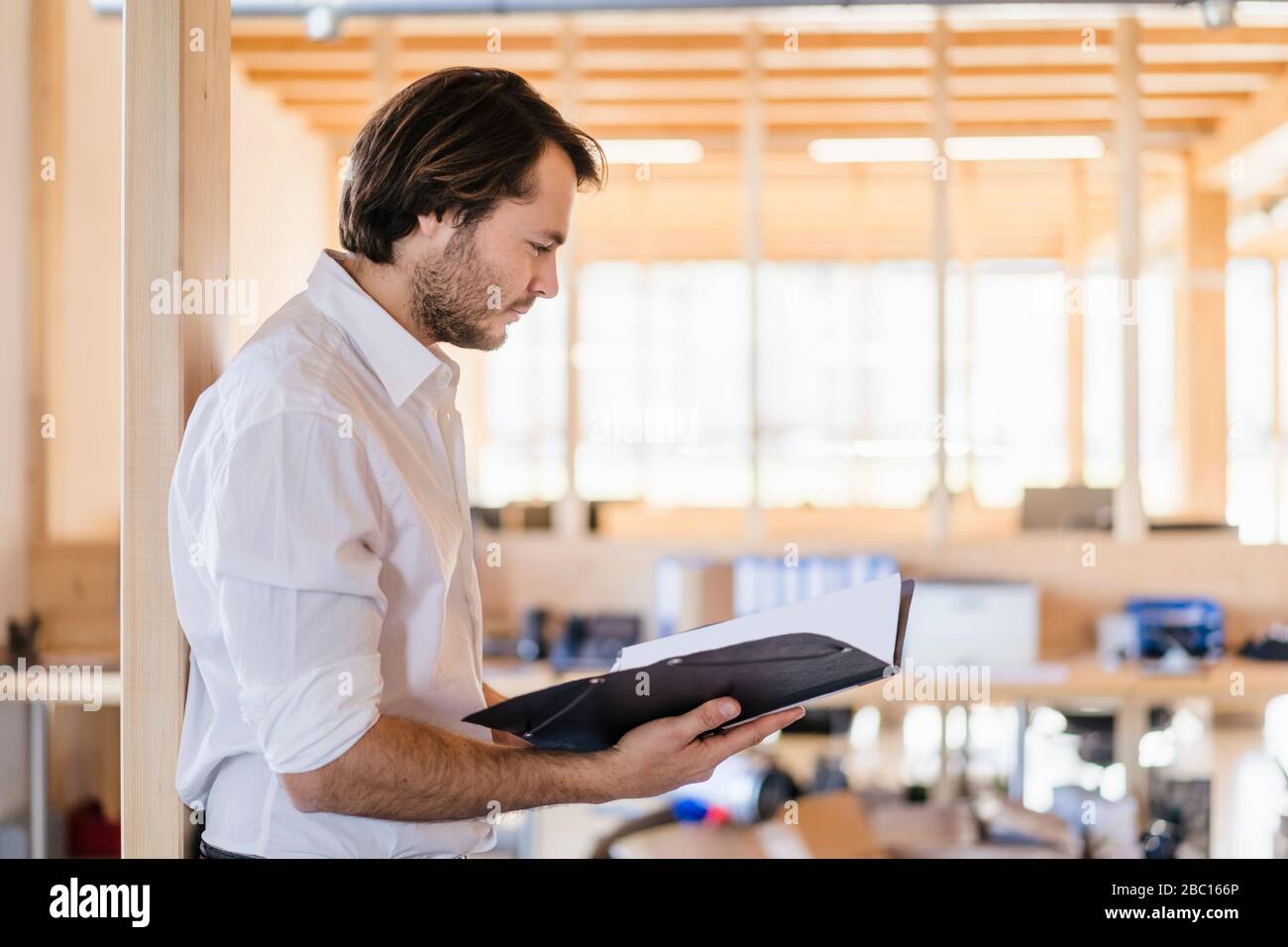 Bbusinessman regardant le dossier dans le bureau en bois ouvert Banque D'Images