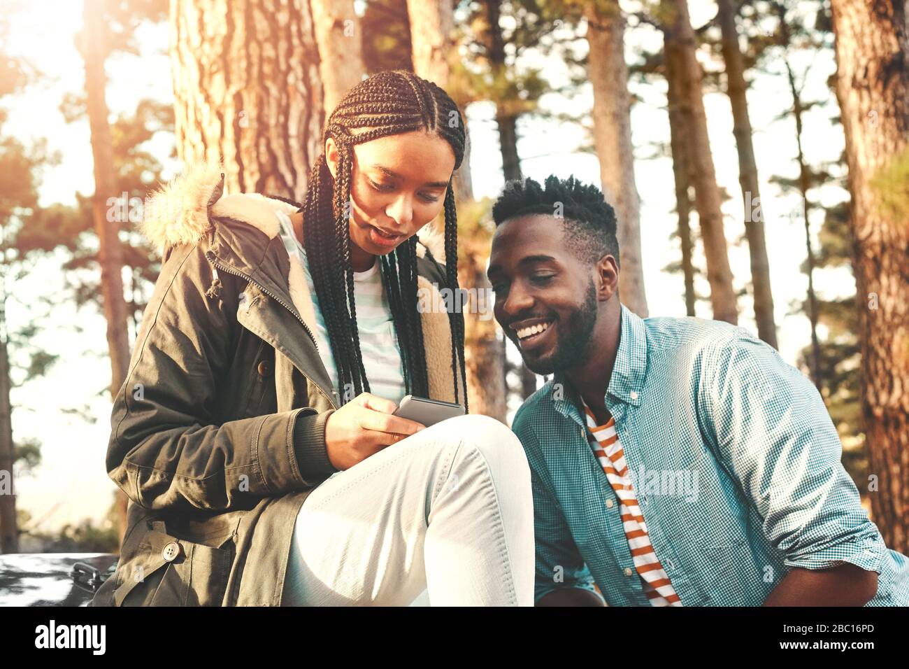 Jeunes couple texting avec smartphone dans les bois Banque D'Images