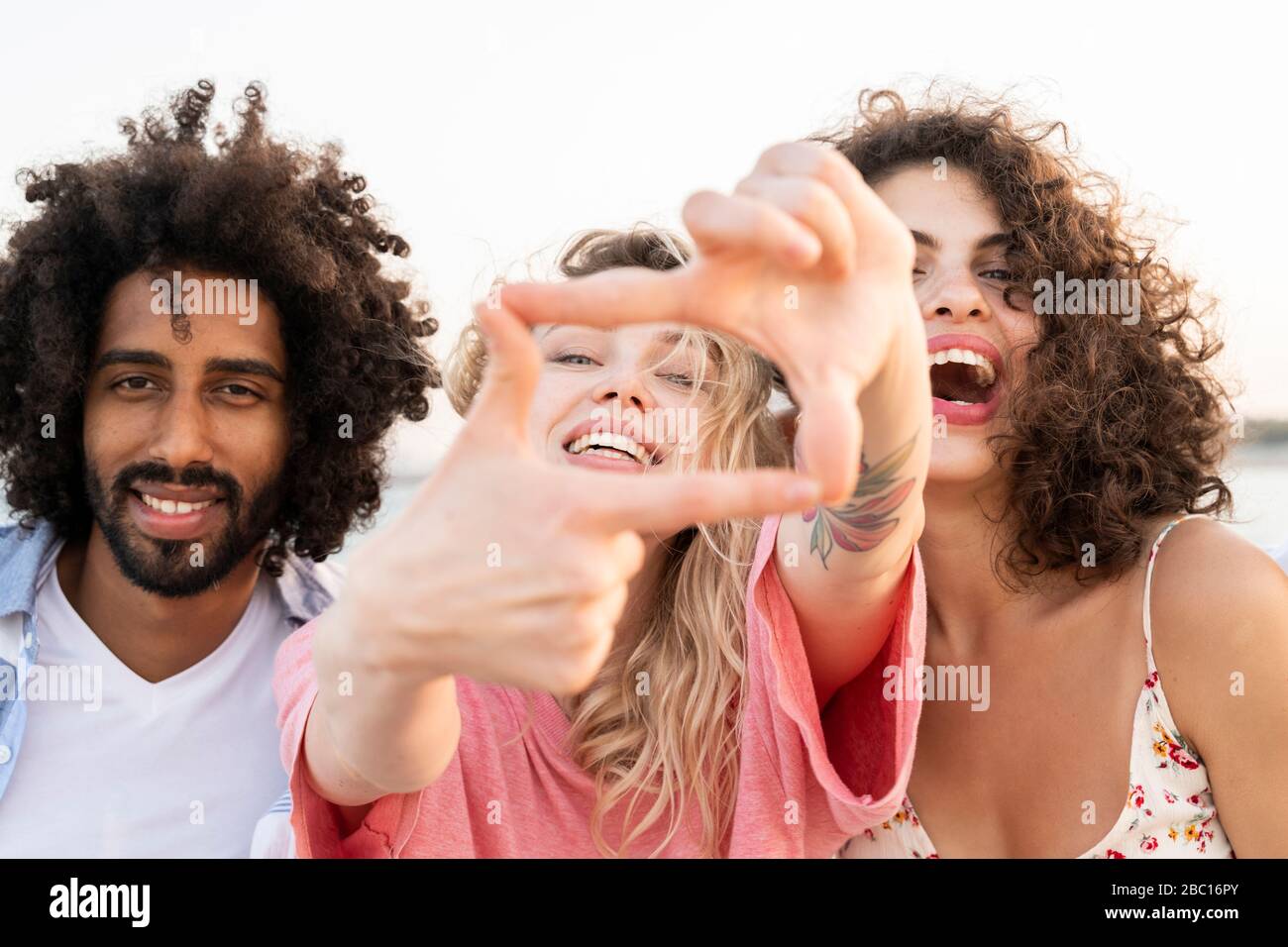 Portrait d'amis heureux à l'extérieur faisant un cadre de doigt Banque D'Images