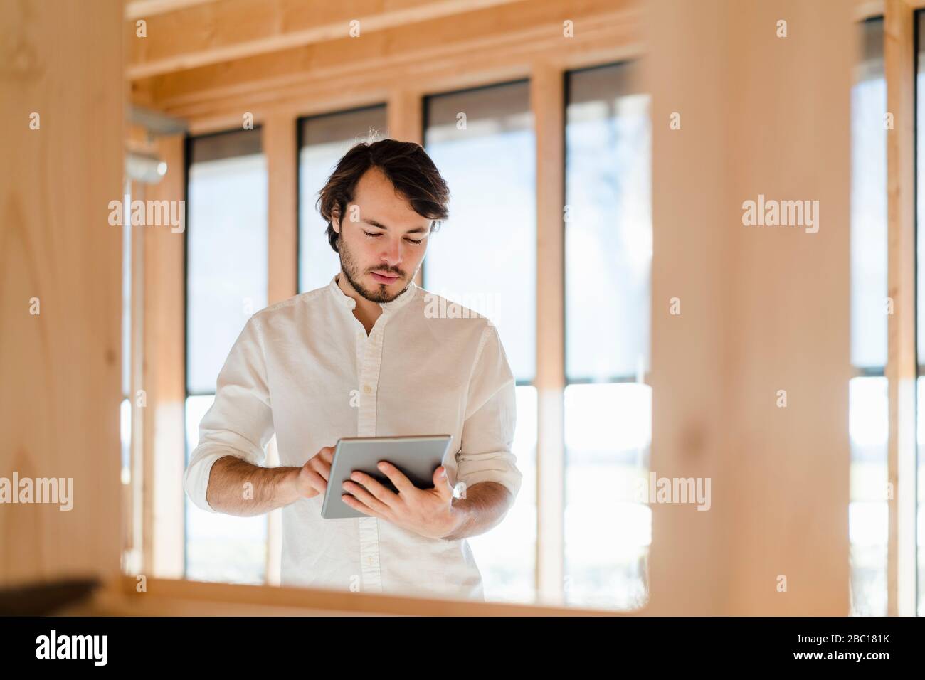 Homme d'affaires utilisant une tablette dans un bureau en bois à plan ouvert Banque D'Images