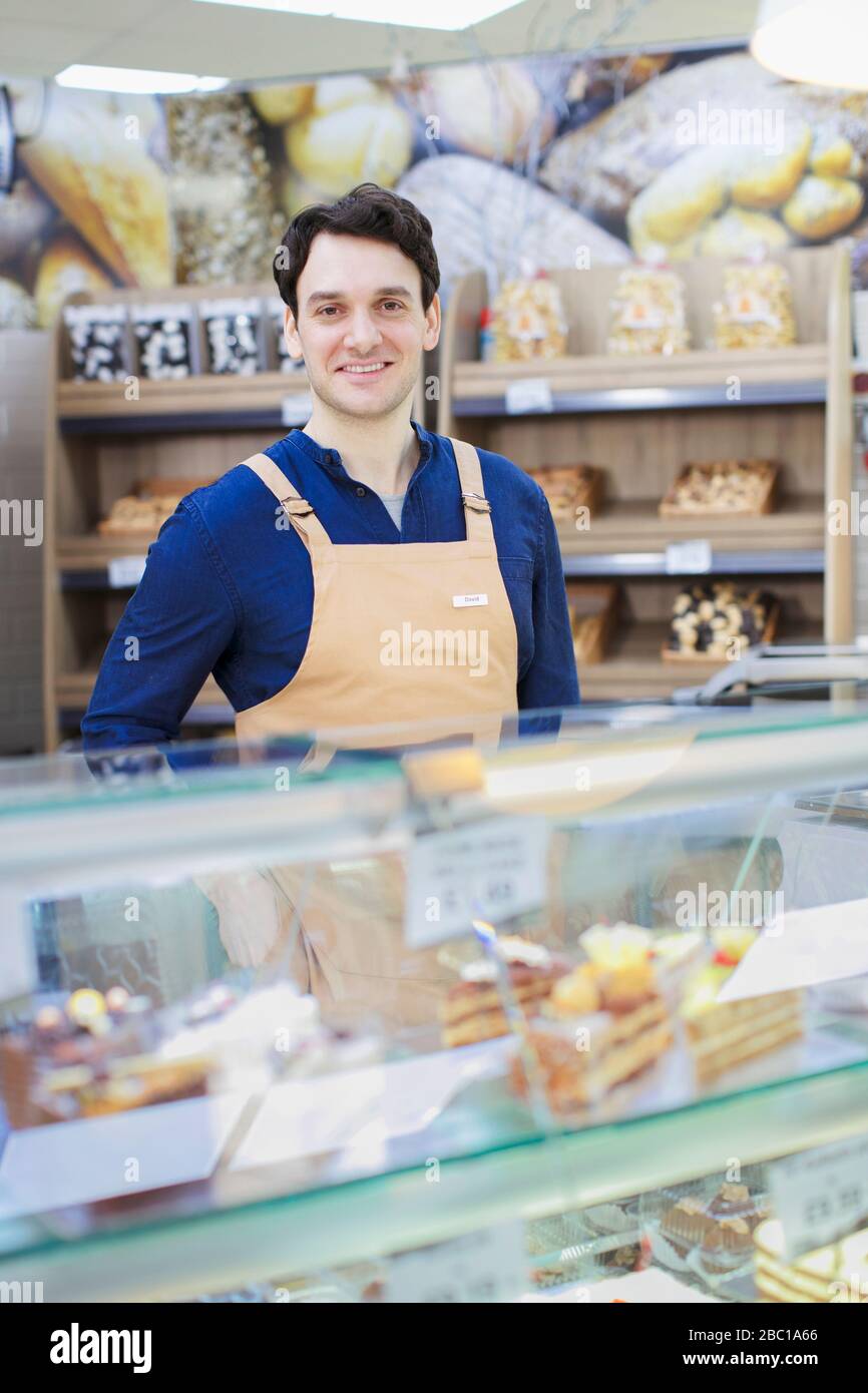 Portrait homme confiant travaillant dans un présentoir de boulangerie dans un supermarché Banque D'Images