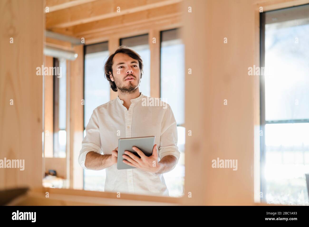 Homme d'affaires utilisant une tablette dans un bureau en bois à plan ouvert Banque D'Images