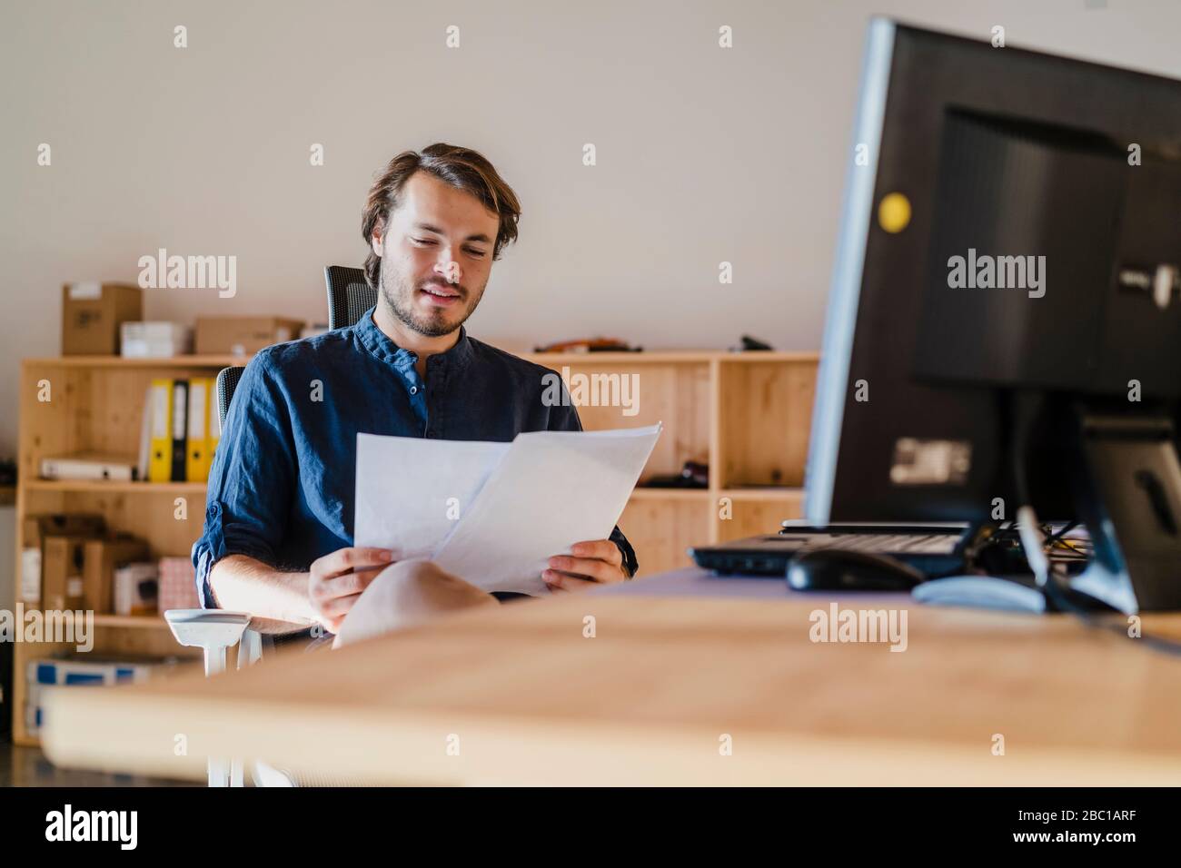 Homme d'affaires lisant des documents au bureau dans un bureau en bois à plan ouvert Banque D'Images