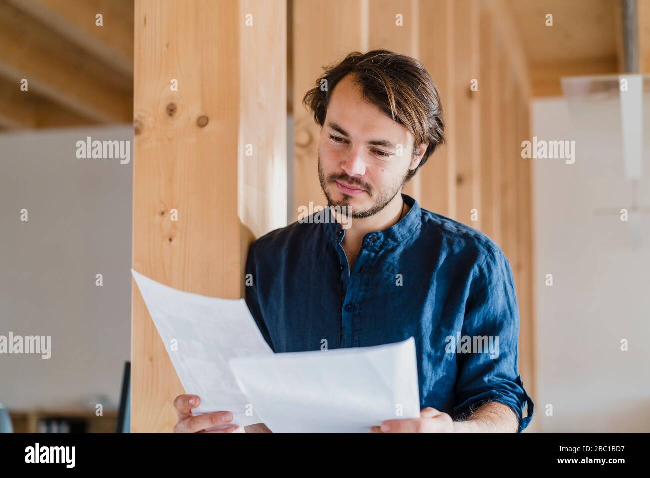 Homme d'affaires lisant le document dans un bureau en bois à plan ouvert Banque D'Images