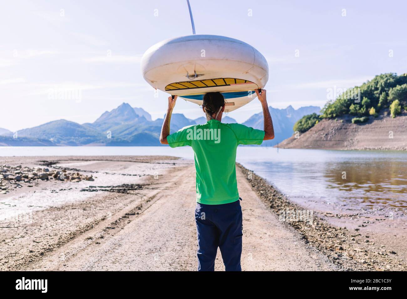 Homme transportant la planche SUP au lac Banque D'Images