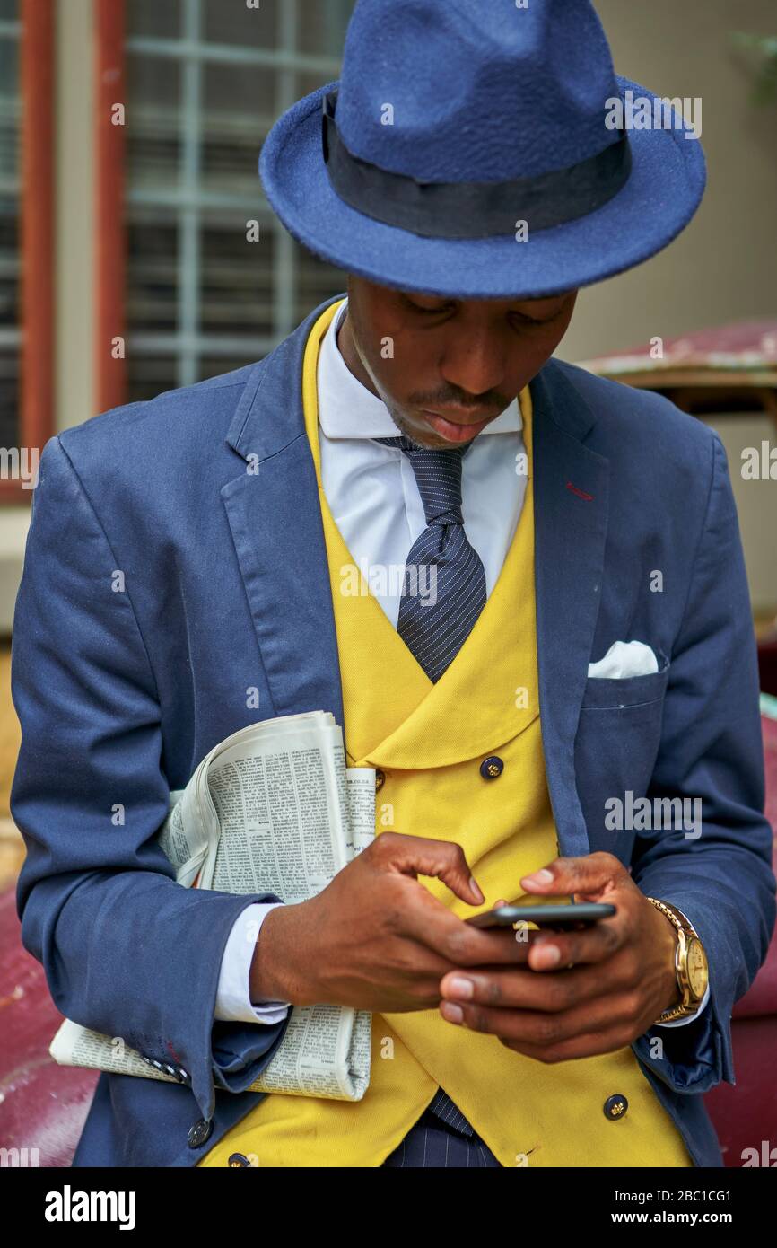 Jeune homme d'affaires portant un costume à l'ancienne et un chapeau  vérifiant son téléphone Photo Stock - Alamy