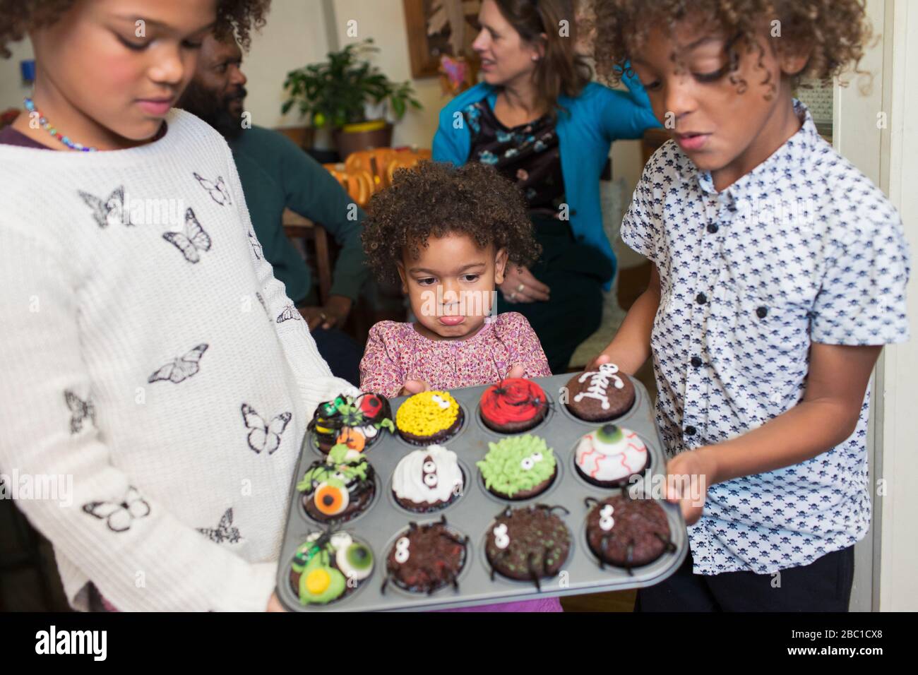Frère et soeurs tenant des cupcakes d'Halloween décorés Banque D'Images