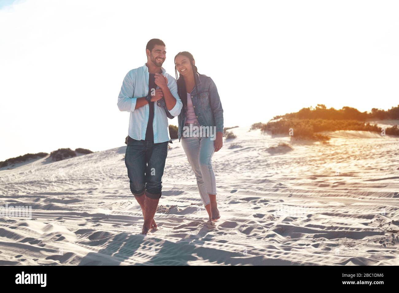 Jeune couple marchant sur la plage d'été ensoleillée Banque D'Images