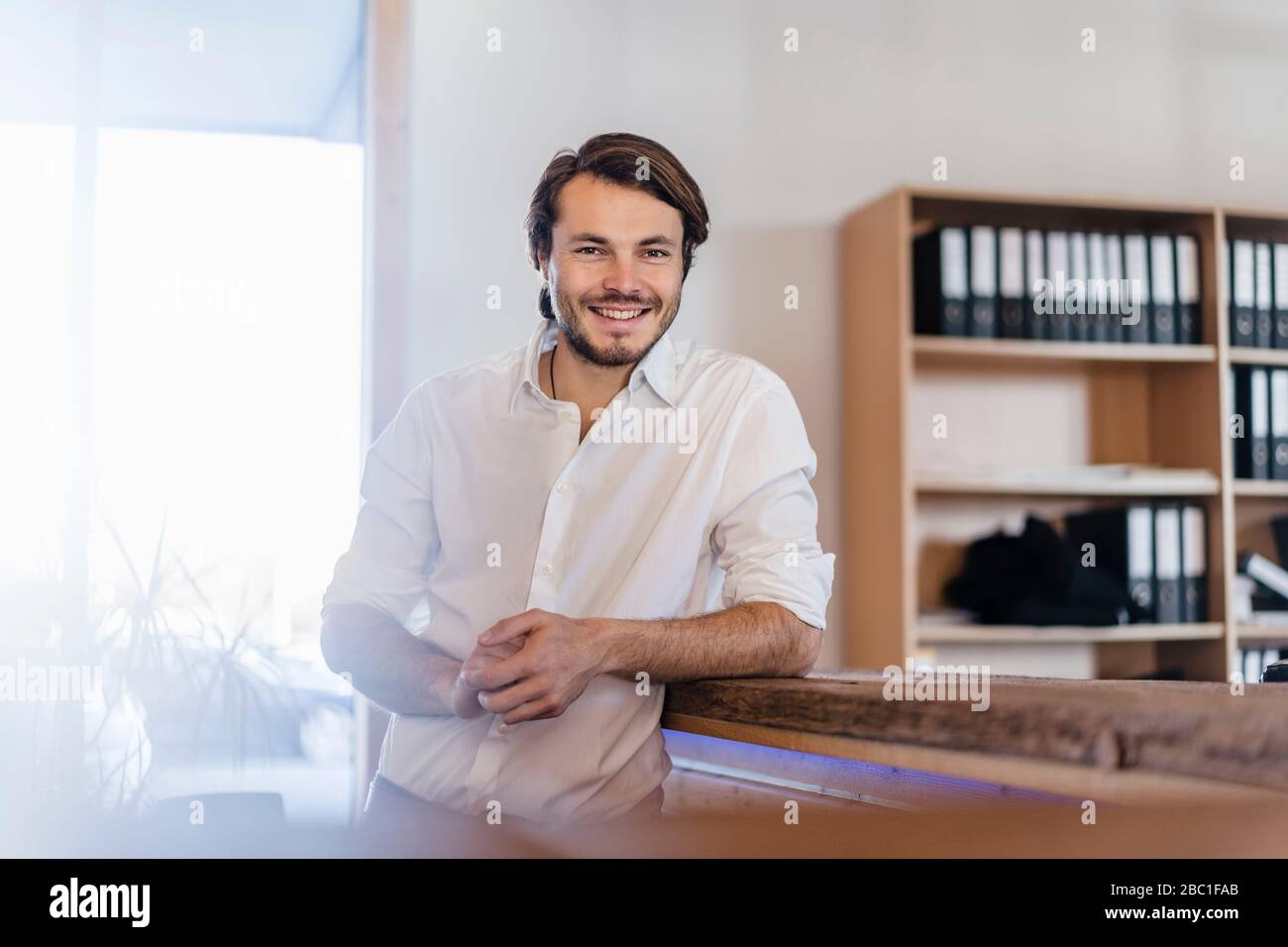 Portrait d'un homme d'affaires souriant dans un bureau en bois à plan ouvert Banque D'Images
