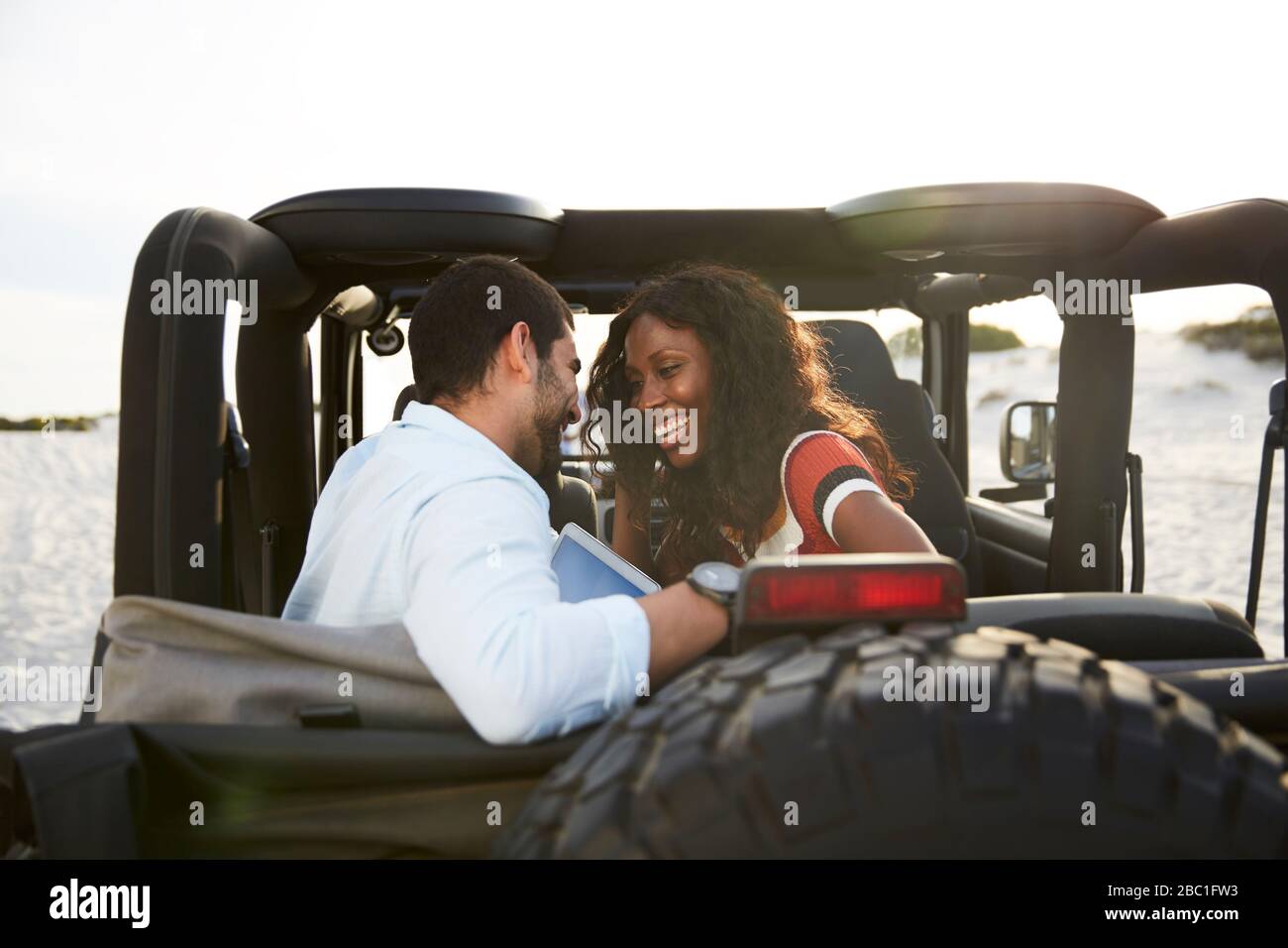 Affectueux jeune couple souriant dans le siège arrière de jeep, en profitant de la route Banque D'Images