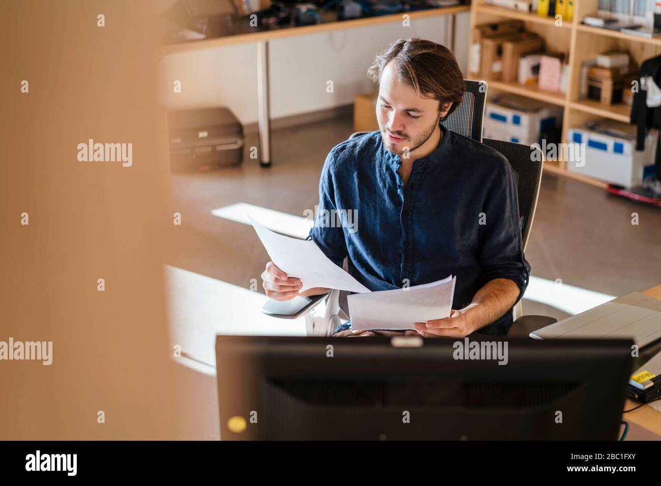 Homme d'affaires lisant des documents au bureau dans un bureau en bois à plan ouvert Banque D'Images
