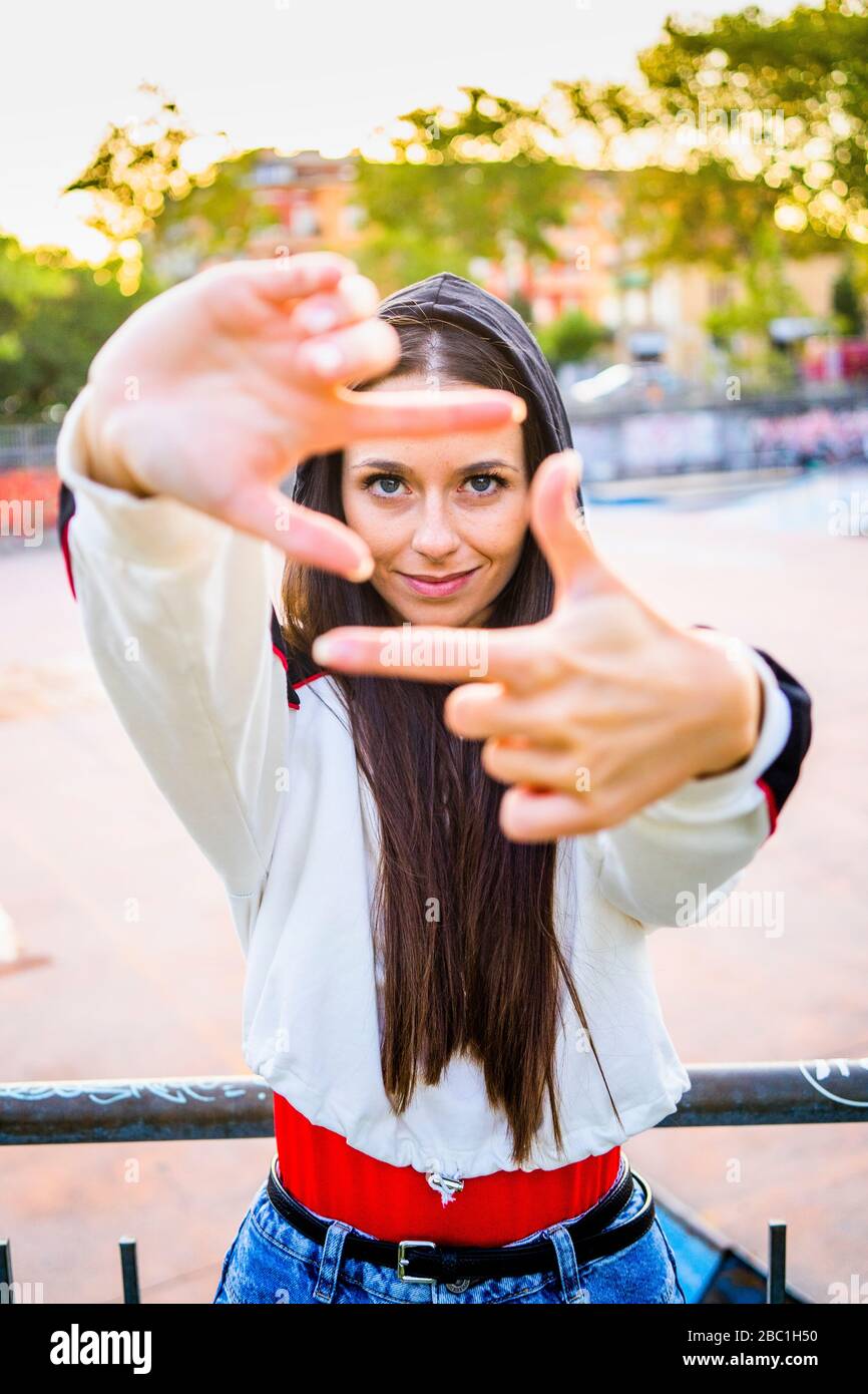 Jeune femme façonnant des cadres avec son doigt au skatepark Banque D'Images
