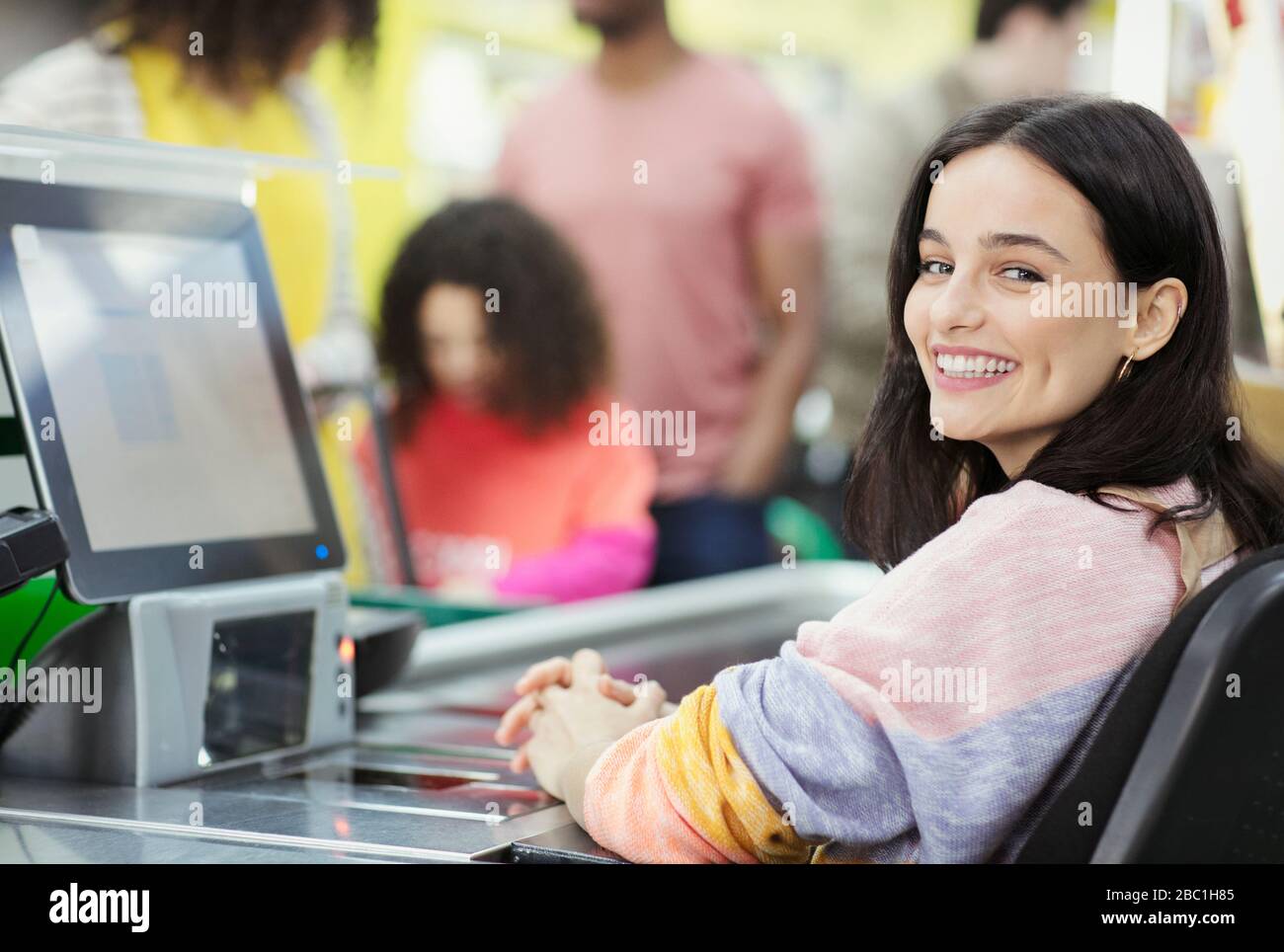 Portrait souriant, confiance femme caissier travaillant au contrôle du supermarché Banque D'Images