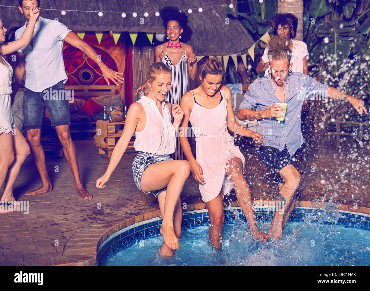 De jeunes amis joueurs qui sautent dans la piscine Banque D'Images