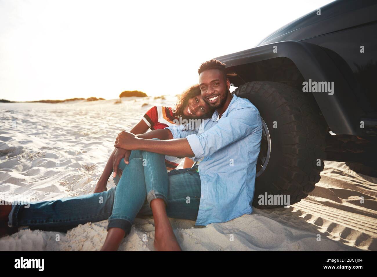 Portrait affectueux jeune couple se relaxant à jeep sur la plage Banque D'Images