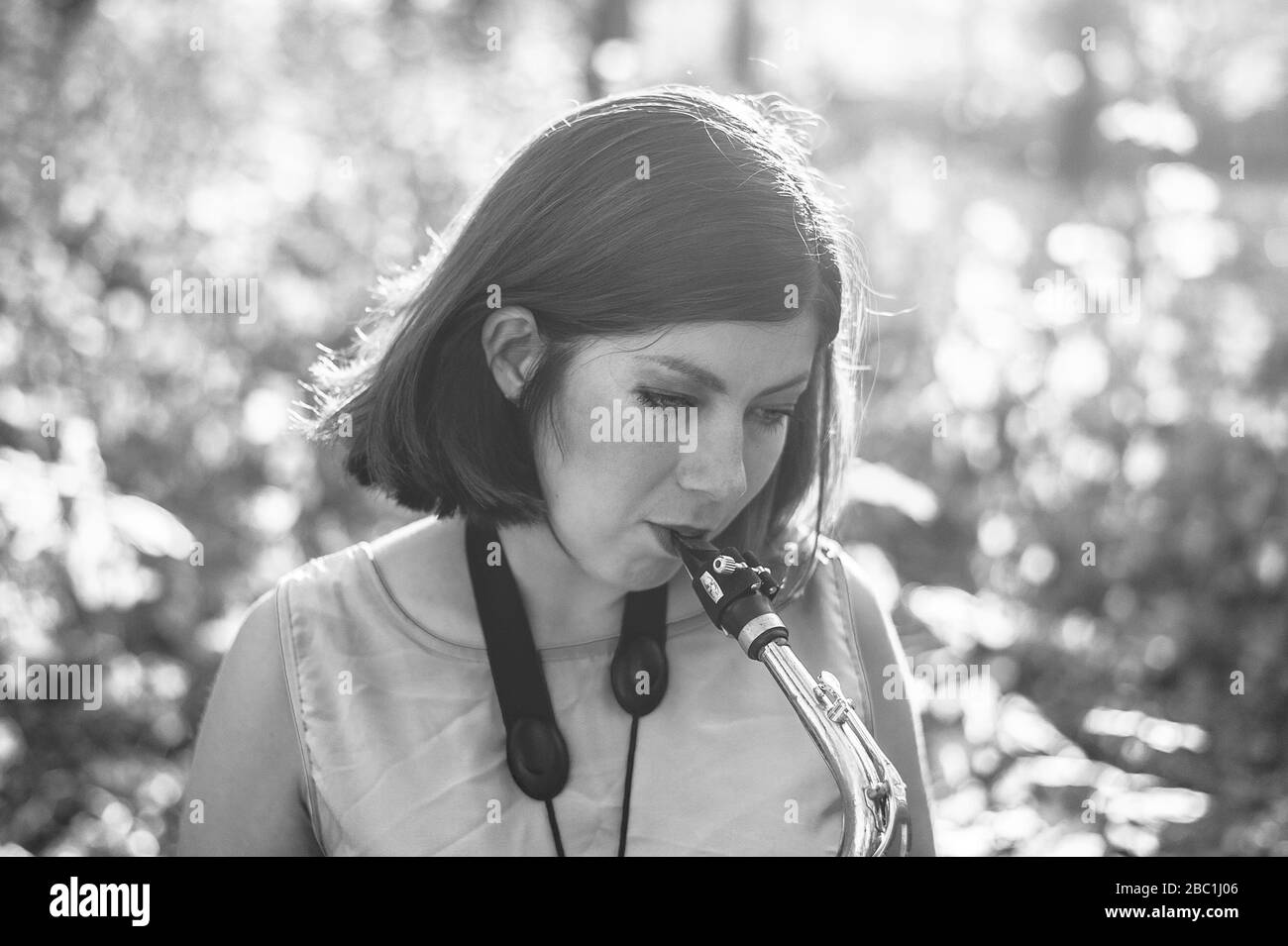 bw portrait d'une jeune fille de brunette jouant le saxophone à l'extérieur Banque D'Images